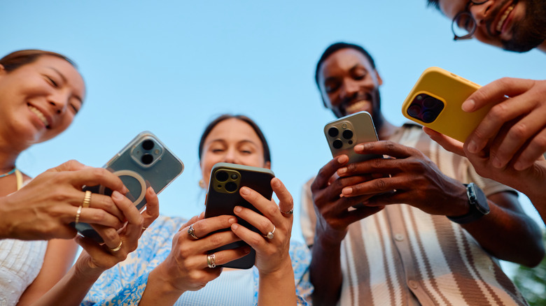 A group of people on their phones, smiling