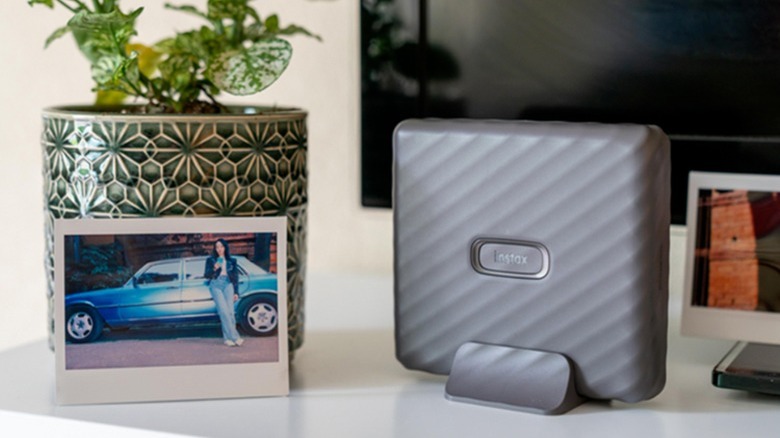 Fujifilm Instax Link Wide printer propped up on a table with a print to its side