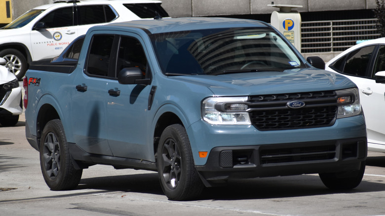 A blue Ford Maverick pick-up truck cruising in the downtown financial district of Houston