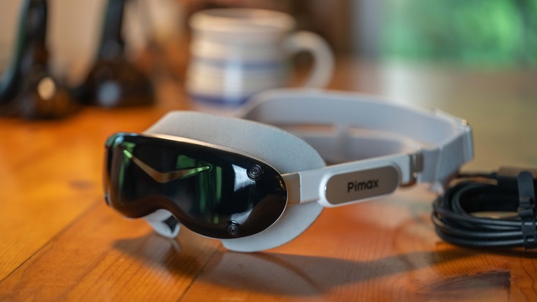 The Pimax Dream VR on a table top with its controllers and a coffee cup in the background.