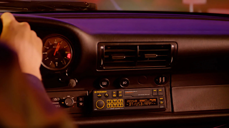 A person driving a car with a Pioneer SXT-C10PS Heritage Single-DIN Digital Media Receiver installed.