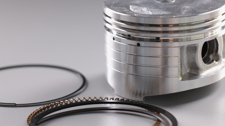 Close-up of piston with three rings beside it
