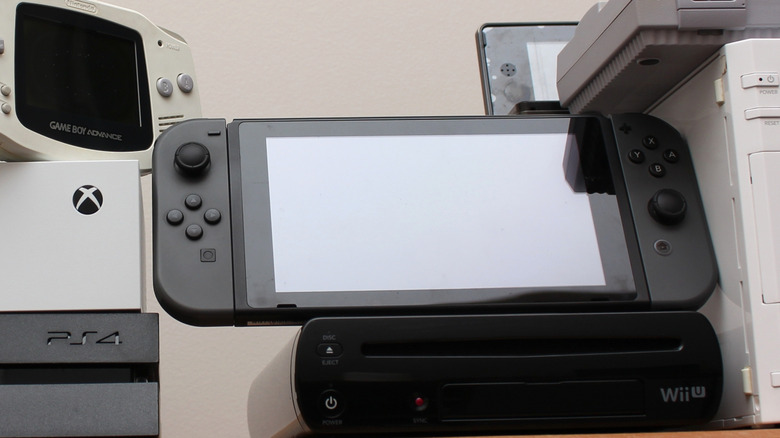 An assortment of gaming consoles, including a GameBoy Advance, Xbox One, PS4, Wii U, Nintendo Switch, 3DS, Wii, and a SNES.