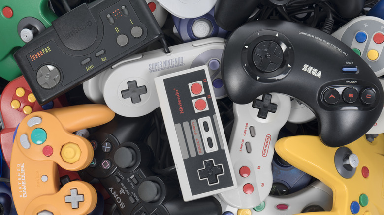 A pile of colorful retro gaming controllers, including NES, SNES, N64, GameCube, and more.