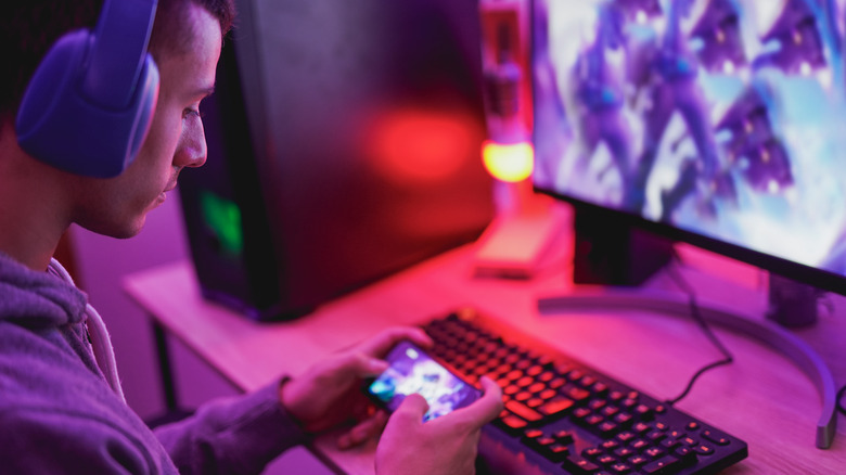 Gamer playing on smartphone and PC