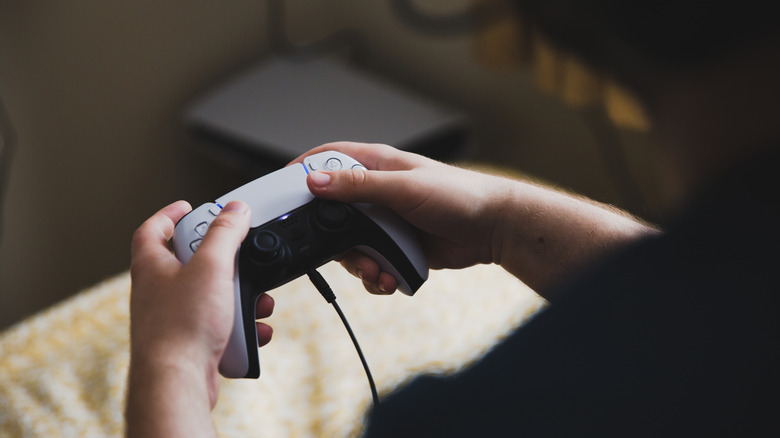 Person holds a charging PlayStation 5 controller.