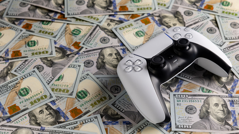 PlayStation controller pictured sitting on top of several $100 bills