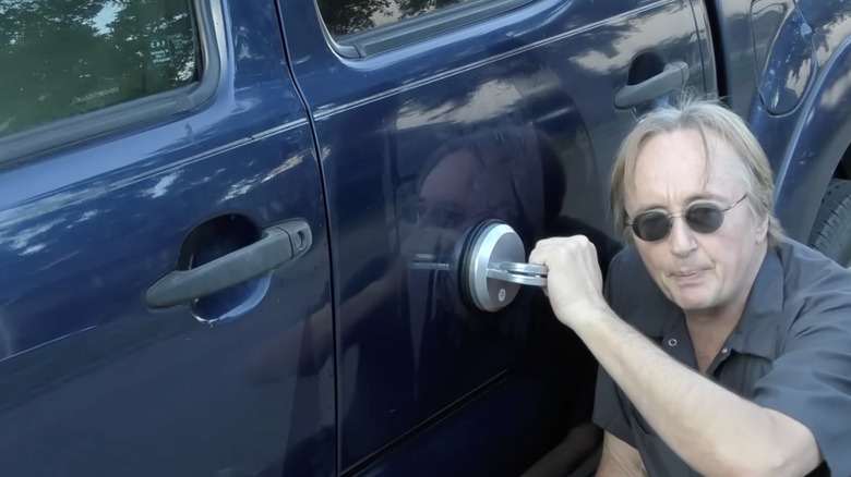 A man fixes a dent using a suction cup