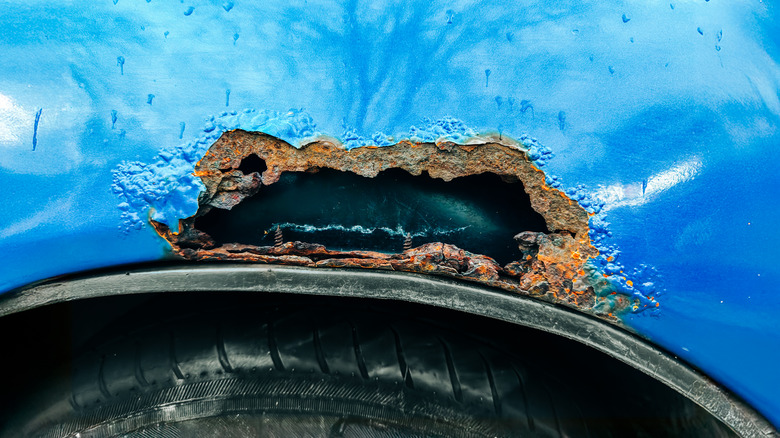 A large rust hole in the side of a car