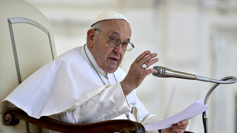 Pope Francis speaking into a microphone