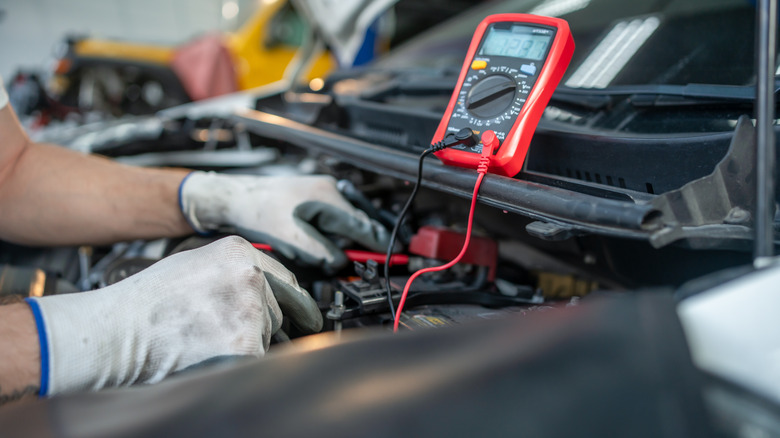 Car mechanic checking voltage on a car battery