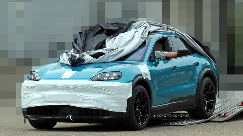 Spy shot of unreleased Porsche Cayenne Turbo GT Coupe with blurred background, front-left 3/4 view with tarp partially covering vehicle