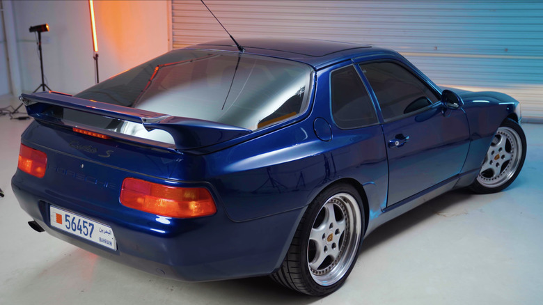 A rare blue Porsche 968 Turbo S photographed from the rear under studio lights in a garage.