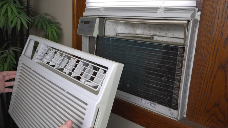 Hands removing window AC front panel