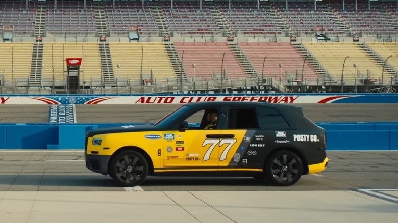 2021 Rolls-Royce Cullinan finished in yellow and black livery with number "77" in pit lane of Auto Club Speedway, left-side view