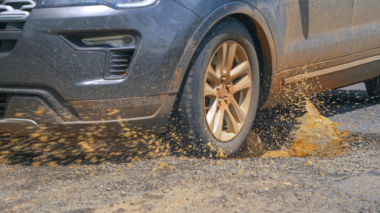 Car hits a pothole with muddy water splashing out