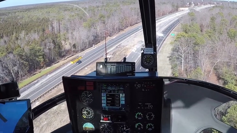 View from pilot's cockpit of helicopter flying over power lines and highway