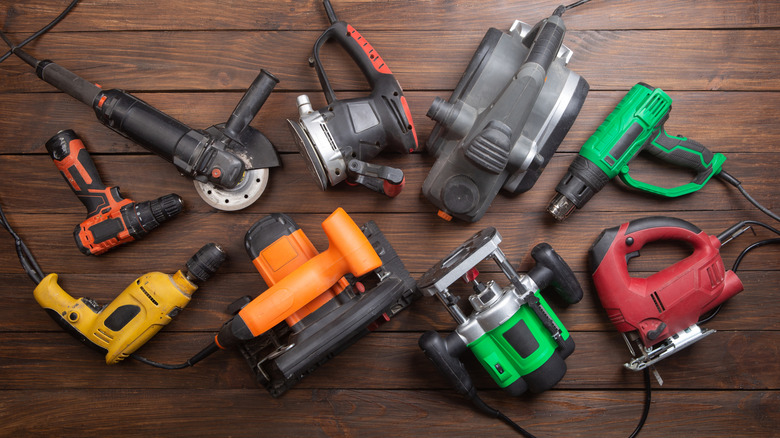 Multiple power tools laid out on a wooden floor