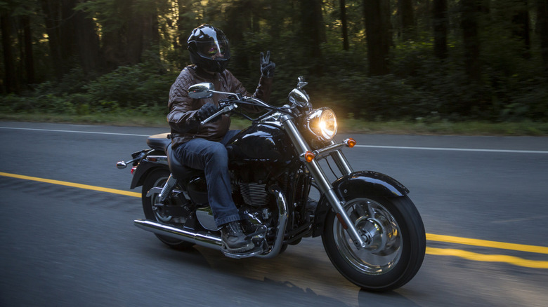 Man riding a motorcycle in the forest at sunset