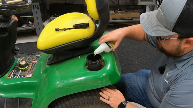 A person adding fuel stabilizer to a lawn mower.