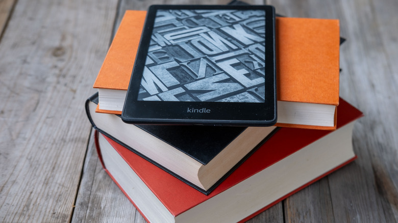 An Amazon Kindle E-reader on a stack of books