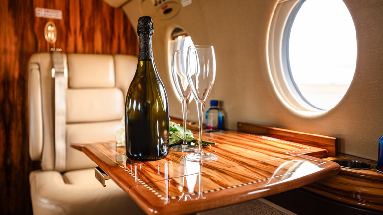 Wide shot of the interior of a private jet, with leather seats, warm wood accents and sleek design