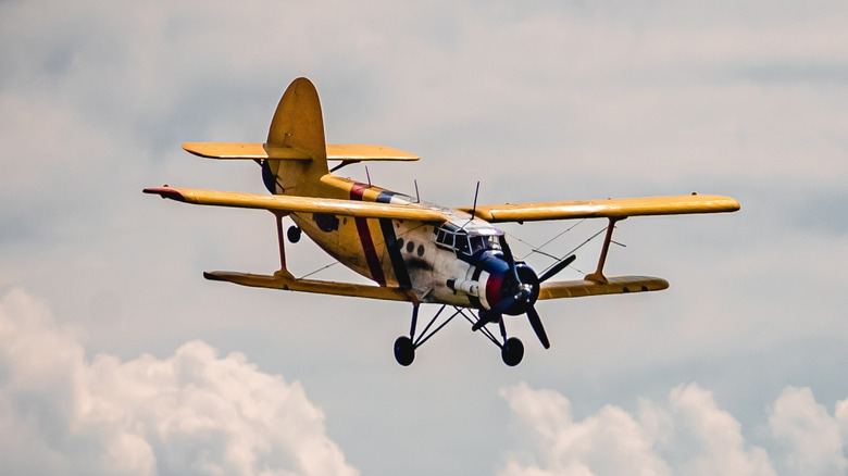 A small yellow propeller plane in the sky.