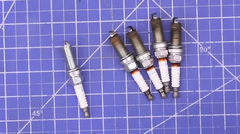 New and used spark plugs on a blue background for comparison
