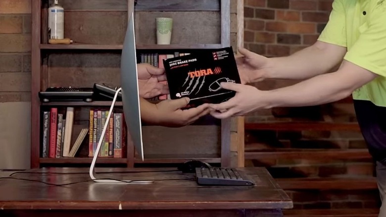 Person being handed a box through a computer monitor