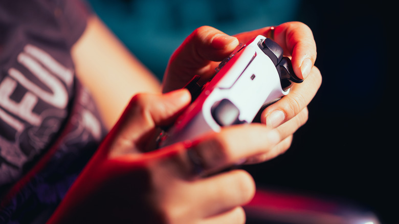 A person holding PlayStation 5 controller