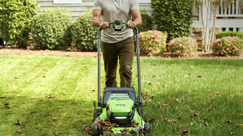 Person using battery powered mower to cut grass