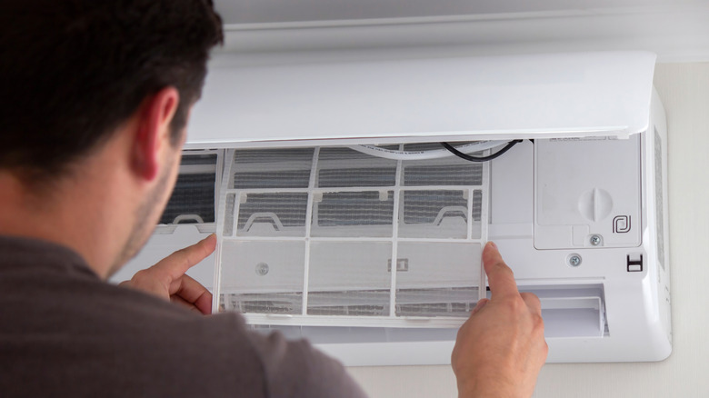 A person checking the indoor unit of an air conditioner