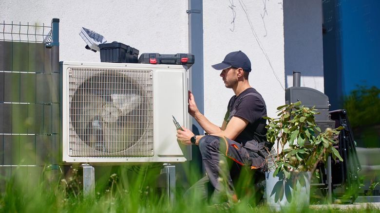 A person working on the outdoor unit of an air conditioner