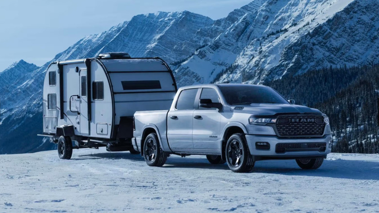 A 2026 Ram 1500 pulling trailer in a snowy, mountainous setting