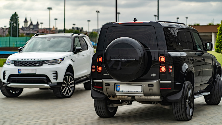 a white land rover discovery parked next to a black land rover defender