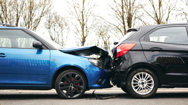 A car accident with a blue car's bonnet destroyed after rear-ending a black car