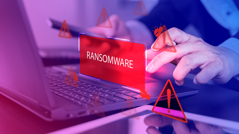 A person using a laptop with a virtual ransomware warning sign laid across it
