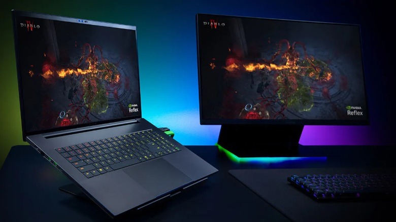Razer Blade laptop beside a gaming monitor.
