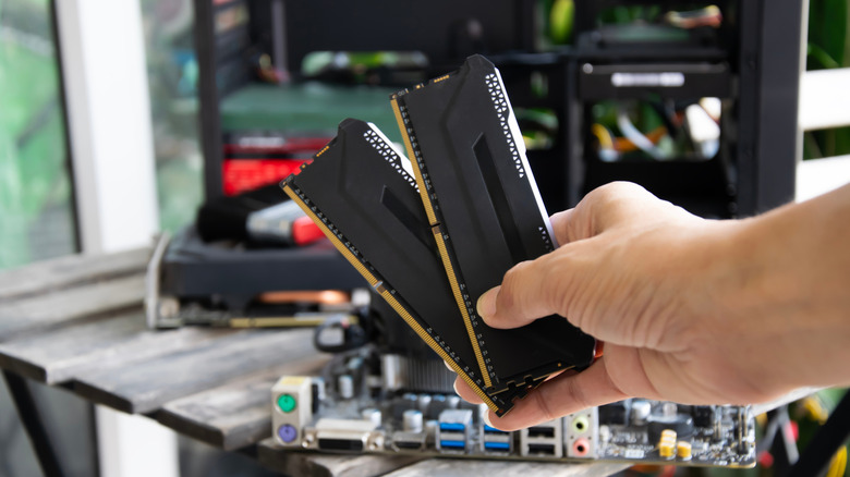 A hand holding out two RAM sticks.