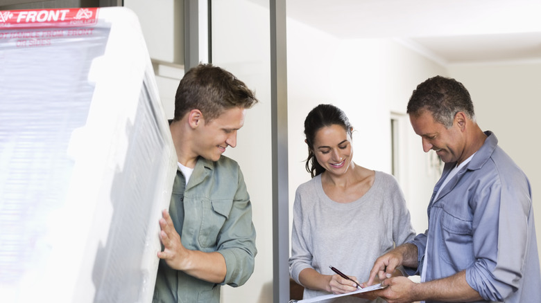 Person delivering a new refrigerator to a couple