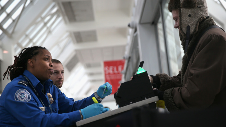 A TSA agent checks a traveler's identification at a special TSA Pre-check lane