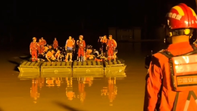 A raft full of people approaching an emergency response worker.