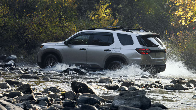 2025 Honda Pilot driving through a rocky stream in the forest