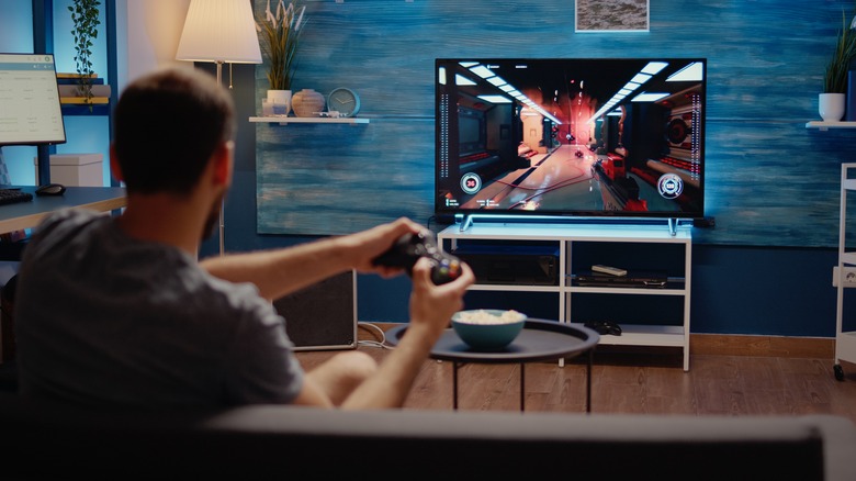 A man games on his TV from his couch