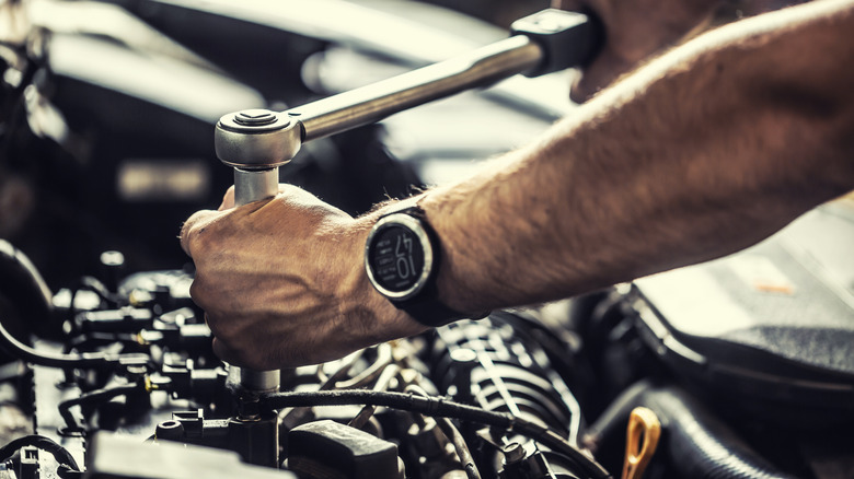 Close-up of mechanic servicing an engine with a torque ratchet