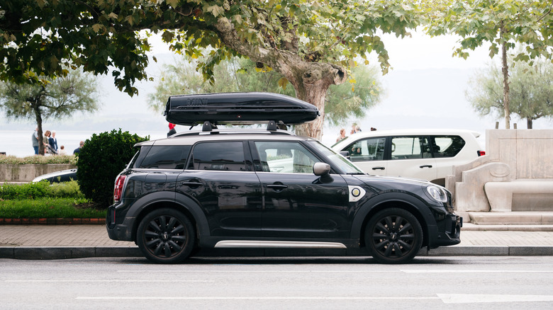 A black car with a roof rack parked on a road