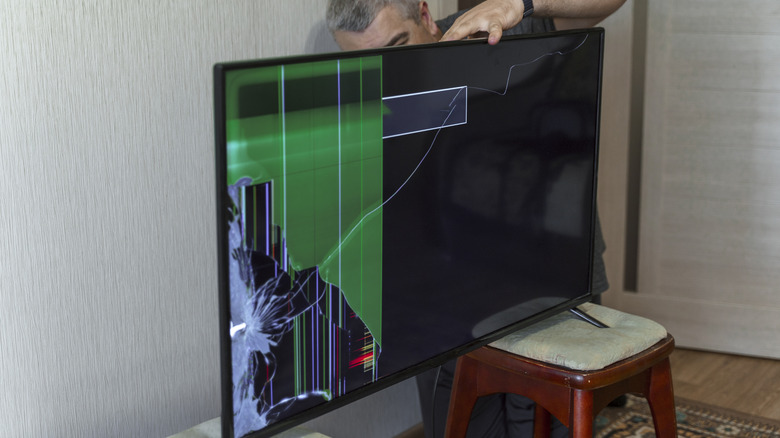Man trying to fix TV with a broken screen