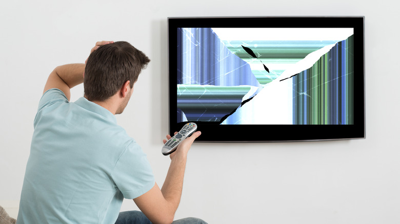 Man looking at broken TV screen