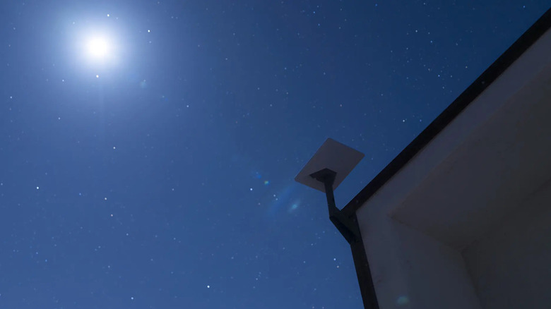 View up at Starlink dish on pillar against starry night sky