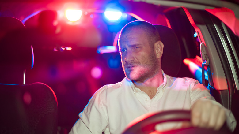 A man sitting in his car, pulled over by the police